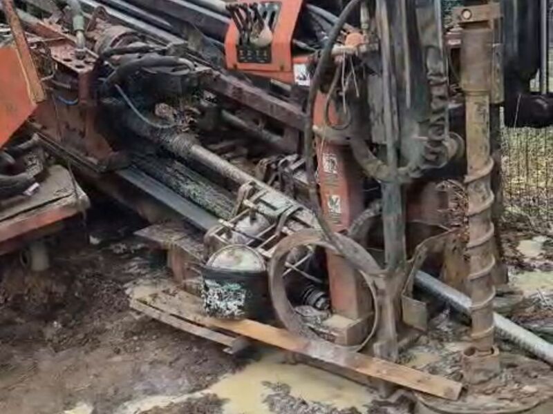 Буровая установка ГНБ с колонной буровых штанг на площадке во время проходки пилотной скважины